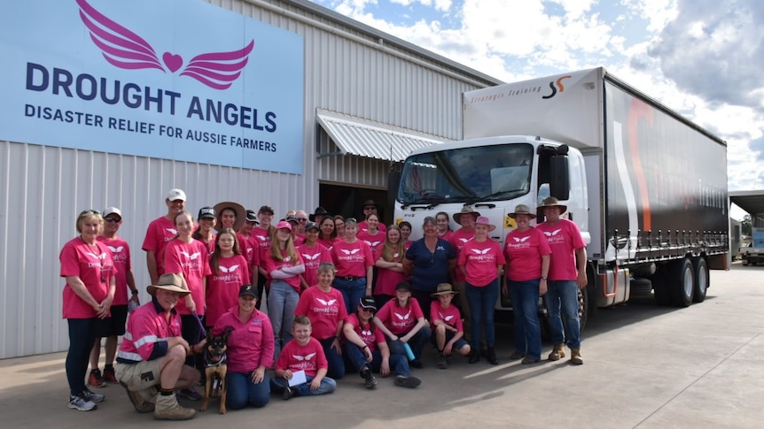 a large truck with a dozen people posing in front of it 