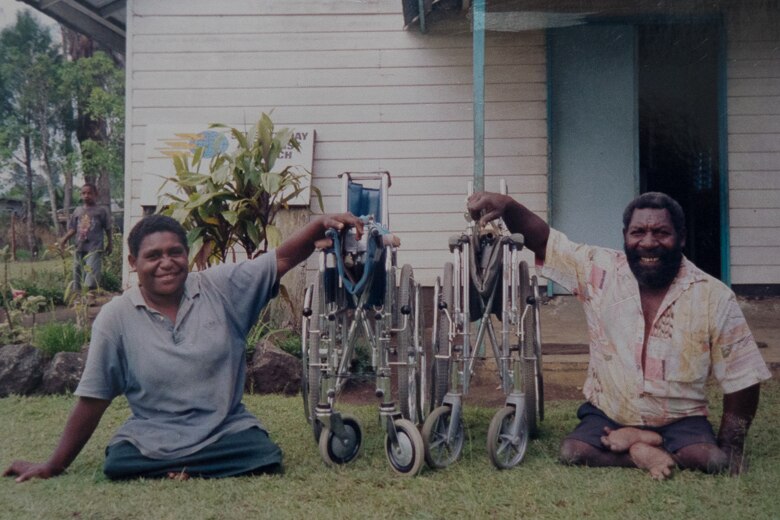 Two men receive refurbished wheelchairs at Kimbe, Papua New Guinea.
