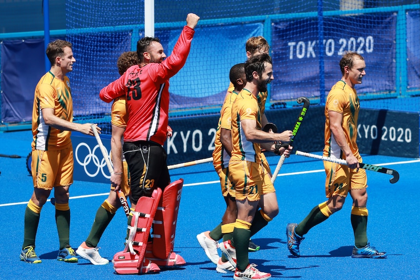 A group of men wearing yellow shirts and shorts walk together on a blue court