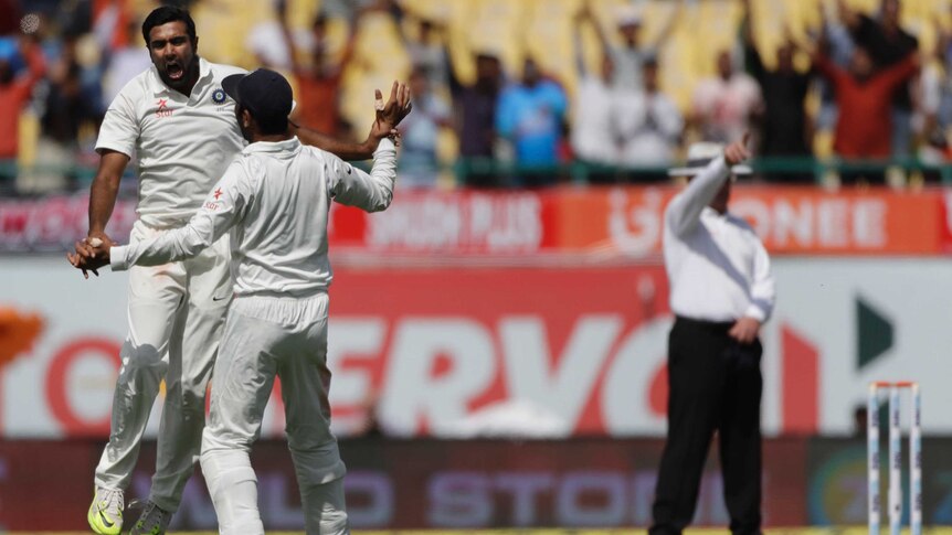 India's Ravichandran Ashwin (L) and Cheteshwar Pujara celebrate dismissing Australia's Steve Smith.