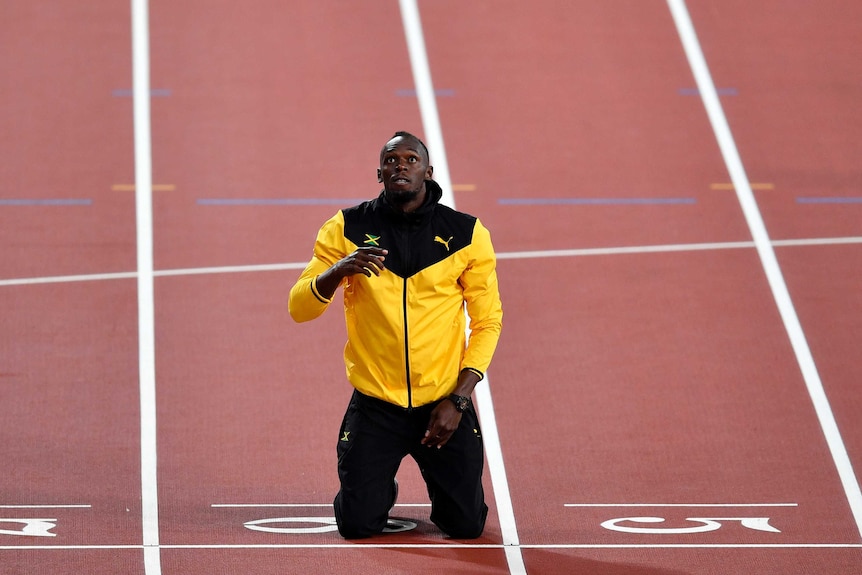 Usain Bolt kneels on the finish line during a farewell lap at London's Olympic Stadium.
