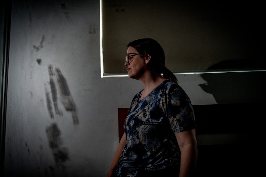 A woman sitting next to a child's fingerprints on a mirror