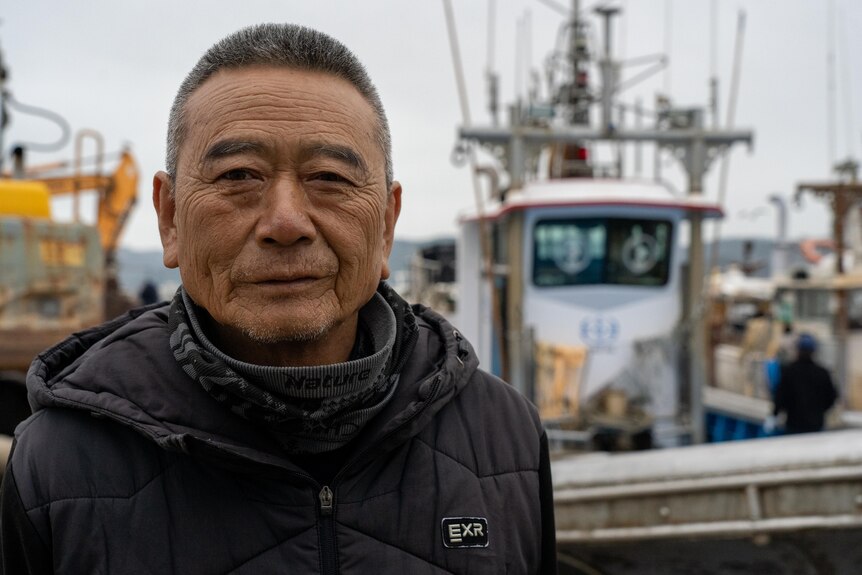 A close up of an Asian man smiling while on board a boat.