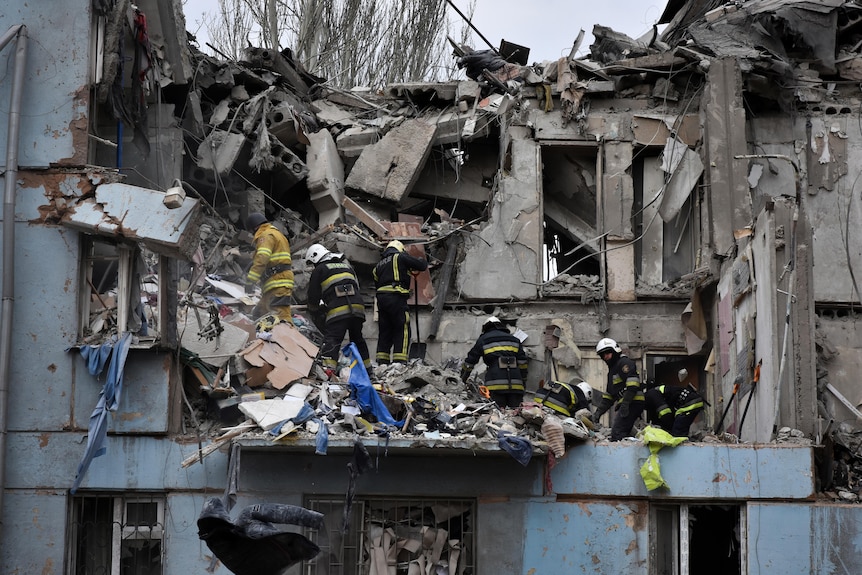 Firefighters pick through the rubble of a building with its second floor almost entirely demolished