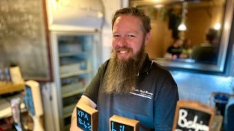 A man at a bar behind beer taps.