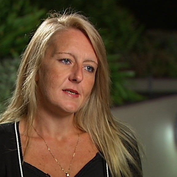 Nicola Gobbo wears a black top as she sits in a dark courtyard facing the side of the camera.