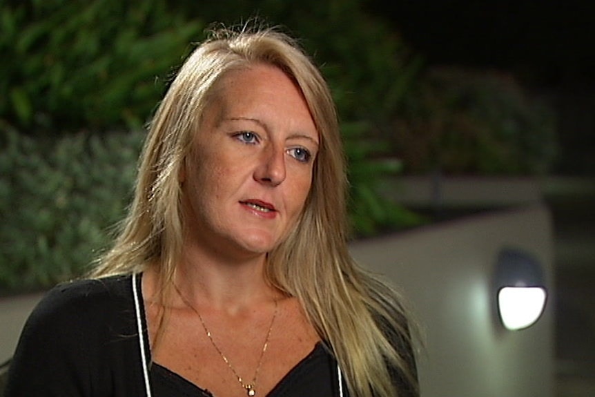 Nicola Gobbo wears a black top as she sits in a dark courtyard facing the side of the camera.