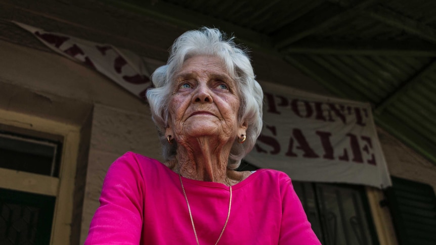 Florence leaning over the railing of the porch outside her Millers Point home