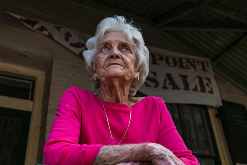 Florence leaning over the railing of the porch outside her Millers Point home