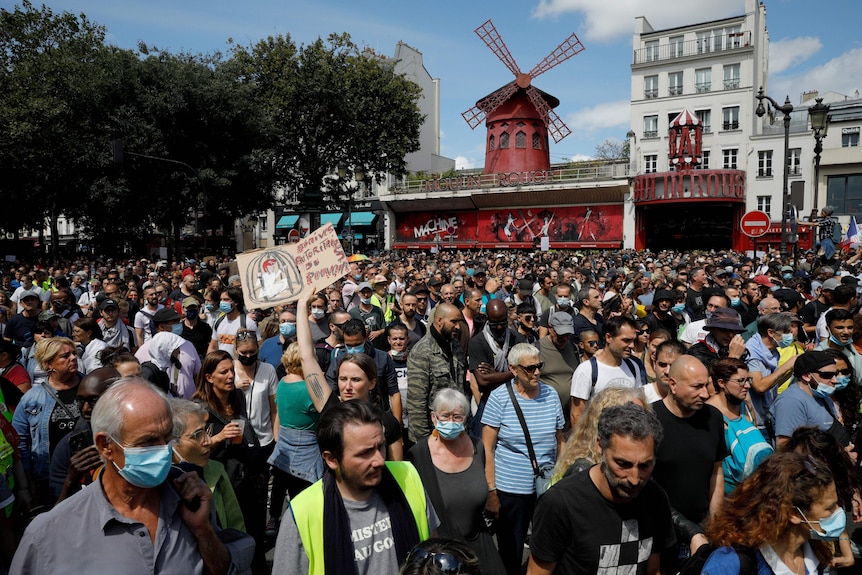 A crowd of people protesting near the Moulin Rouge windmill
