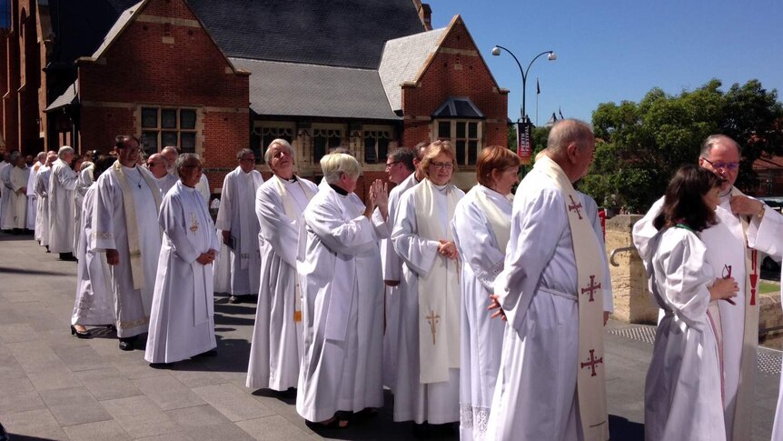 A line of Anglican clergy wearing white vestements  outside St George's Cathedrral.