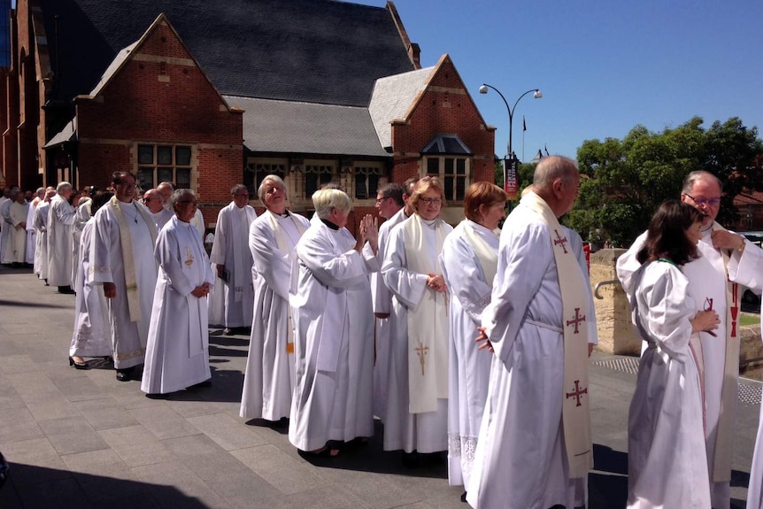 A line of Anglican clergy wearing white vestements  outside St George's Cathedrral.