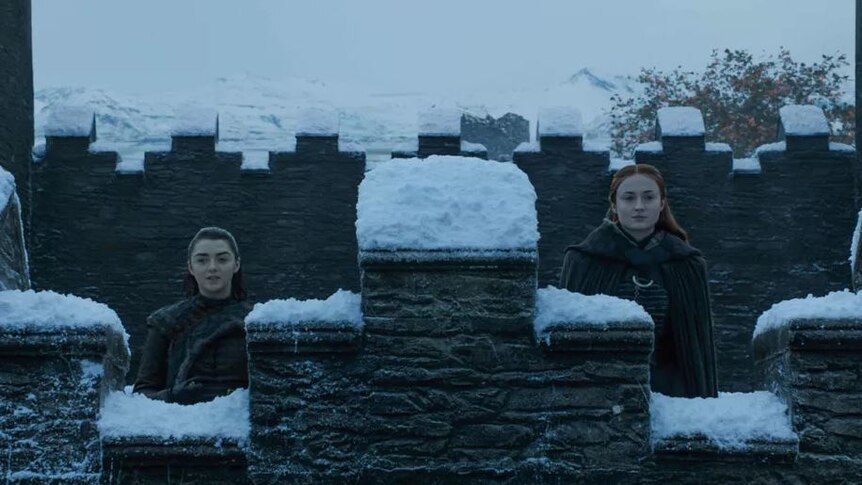 Arya and Sansa look out from the wall of Winterfell