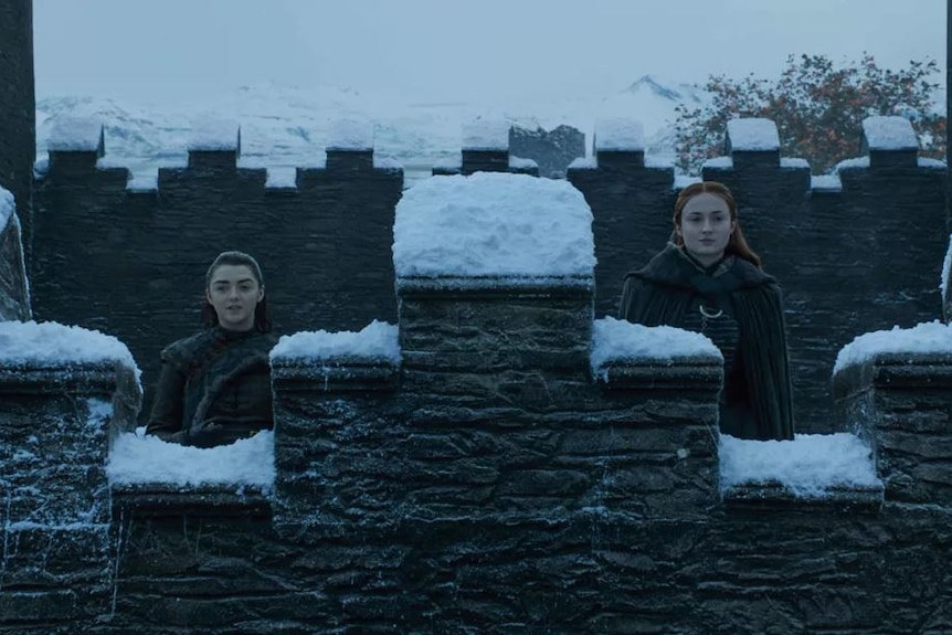 Arya and Sansa look out from the wall of Winterfell