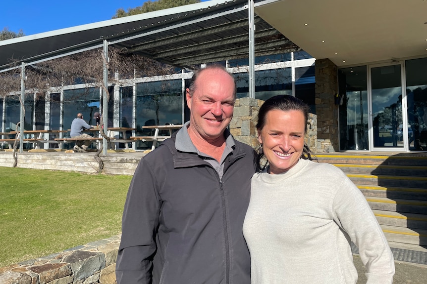 Man and Woman pose for photo in fron of golf club  