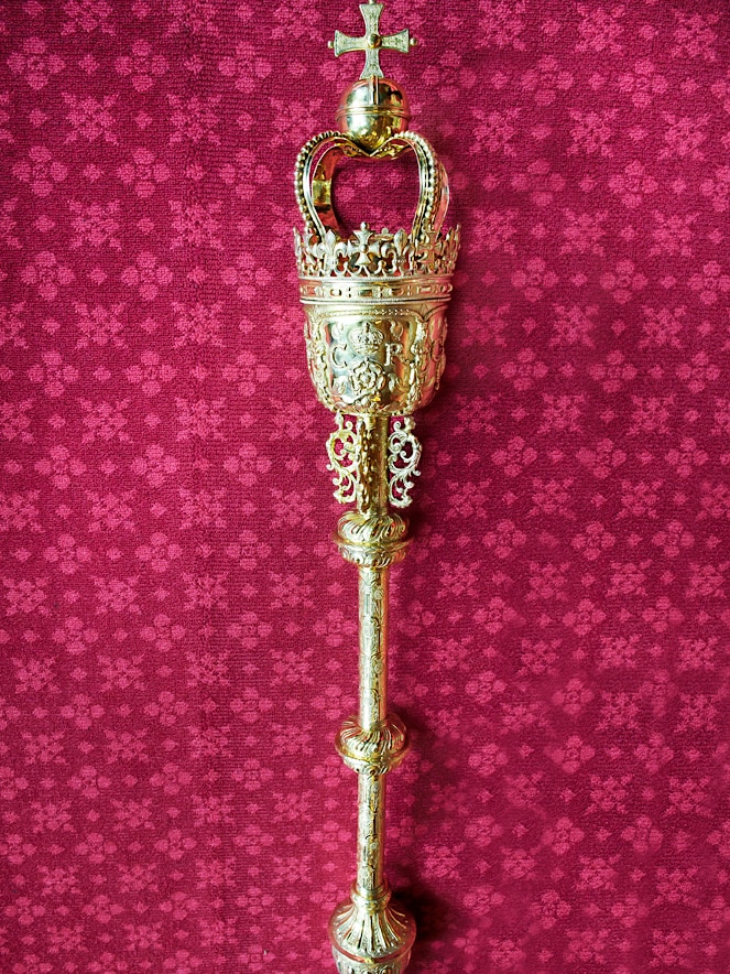 An ornate golden mace with a crown motif on top.