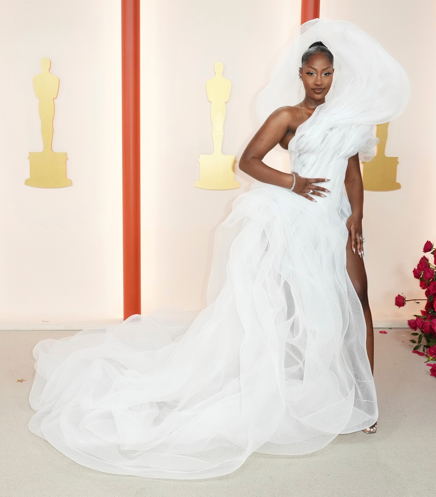 Tems wearing a white off-the-shoulder tulle gown with a long puffy train and a structured hood