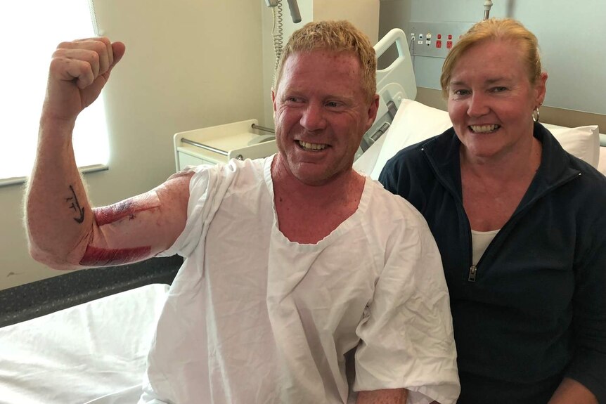 man and woman smiling as man flexes biceps with bloody bite marks