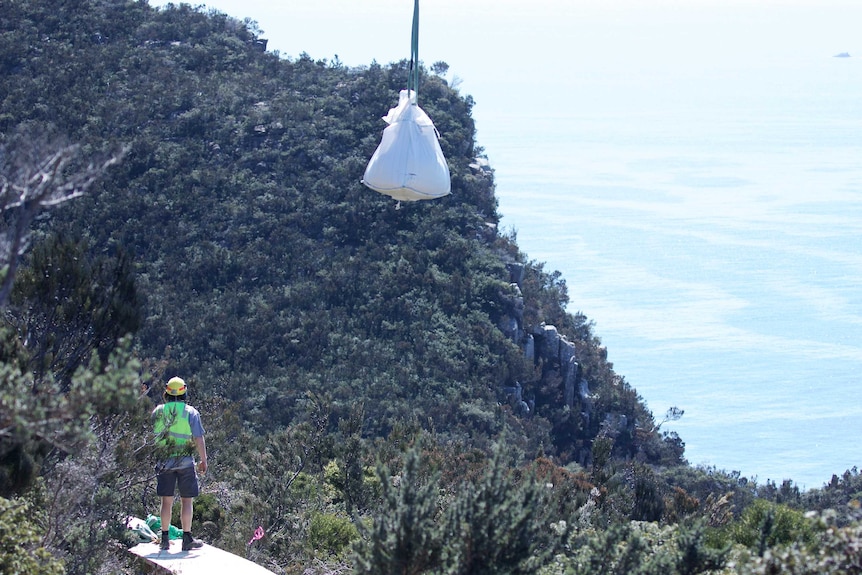 A worker receives materials for the Three Capes Track