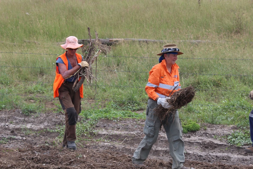 BlazeAid volunteers Carlia Richardson and Penny Carson pick up sticks and debris.