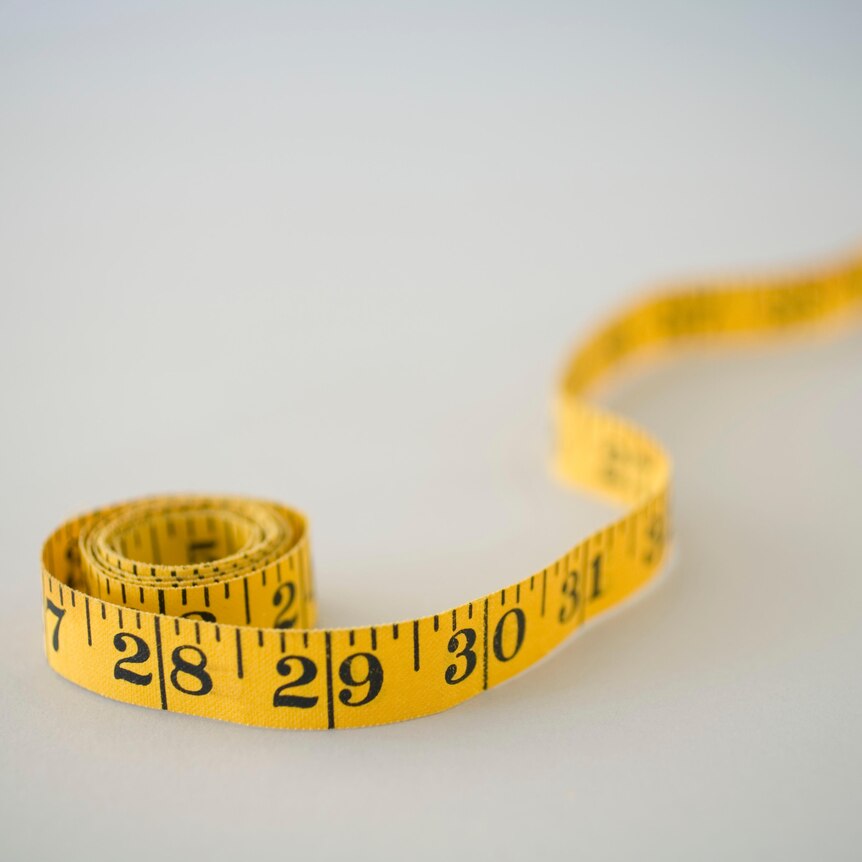 A close up of a roll of tape measure with some unravelled