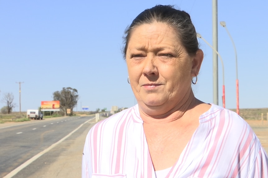 Close up shot of woman in pink and white striped shirt standing in the outback