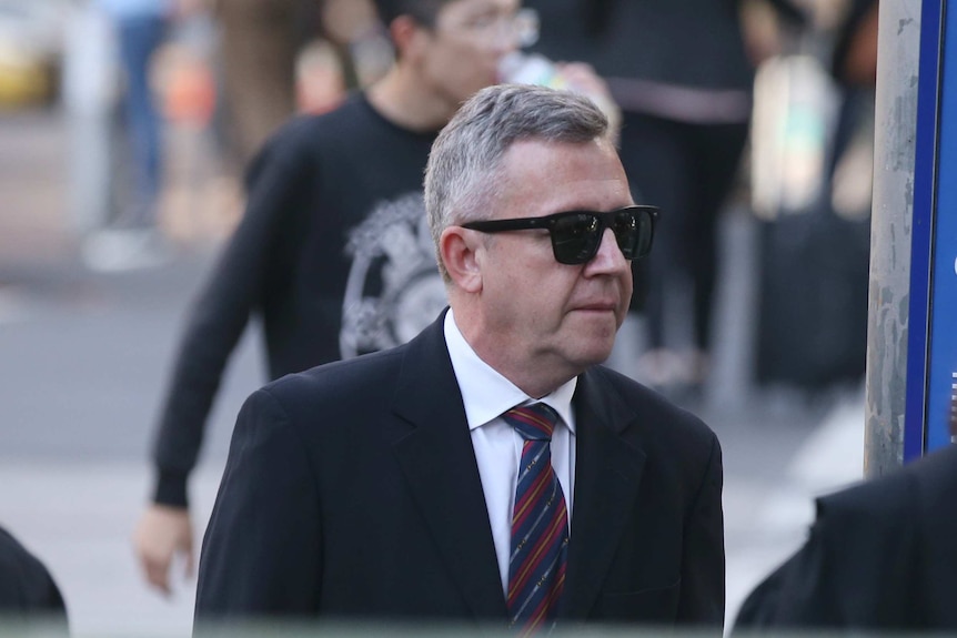 Philip Murphy, dressed in a suit and sunglasses, walks outside court.