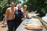 Thee men standing together with a catch of fish