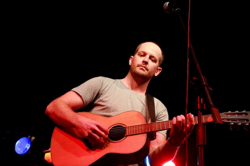 Musician Brad Butcher on stage with his guitar