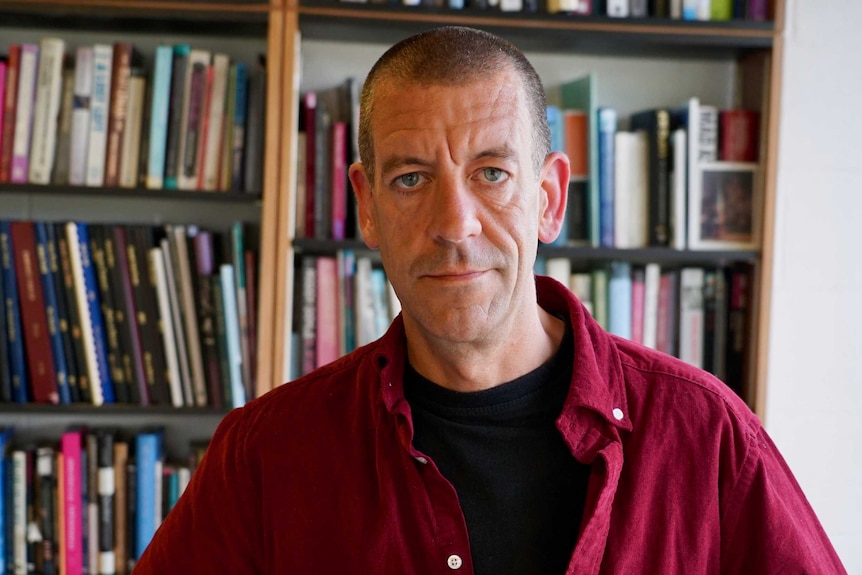 Diarmaid Ferriter stands in front of a bookshelf