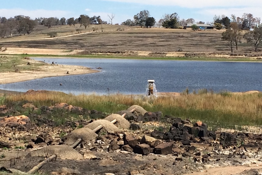 A dam, with little water remaining, set in an arid, dry looking landscape