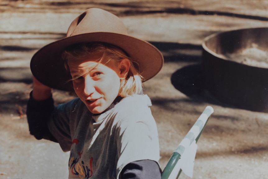 An old photo of a young girl wearing a large hat and looking at the camera.