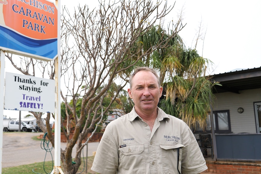 A man standing near a caravan park sign.