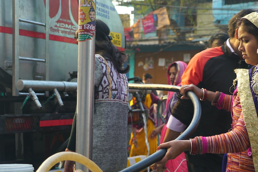 A local woman fills up a container from a water truck.