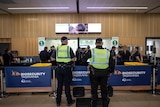 two police in high vis vests stand back-on to the camera at Hobart Airport 