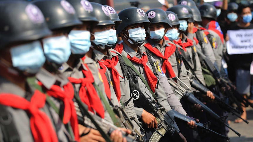 Armed riot police are seen near protesters in Naypyitaw, Myanmar.