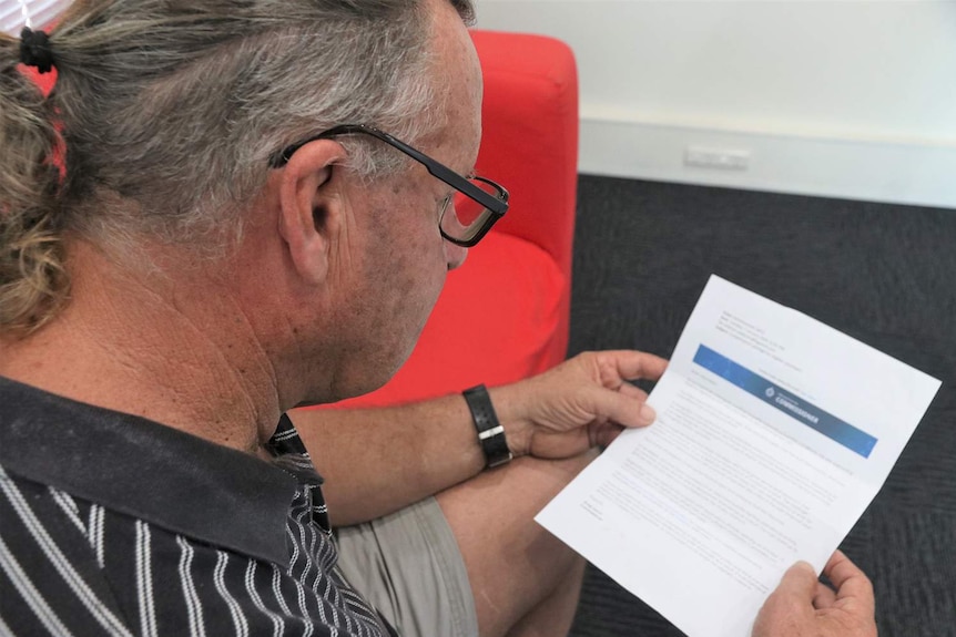 Volunteer rural firefighter Andrew Ruddock sits looking at a compensation letter.