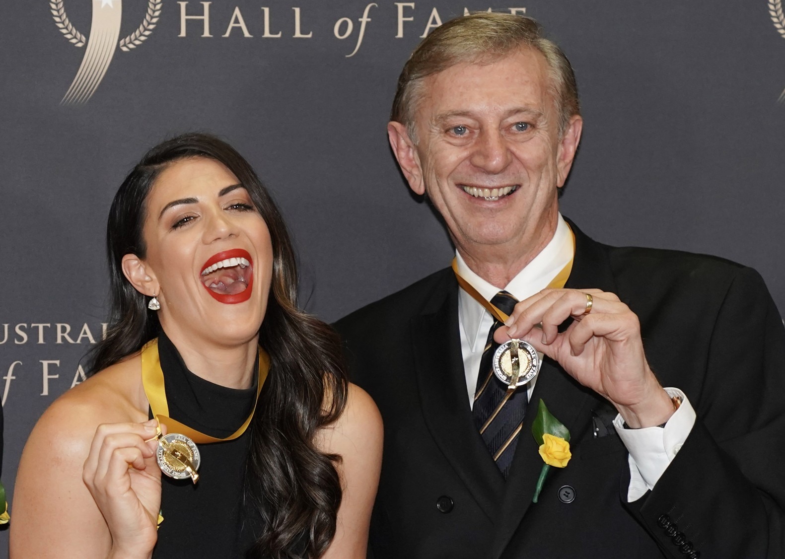 Dennis Cometti, na foto com a nadadora Stephanie Rice, segura uma medalha e sorri. 