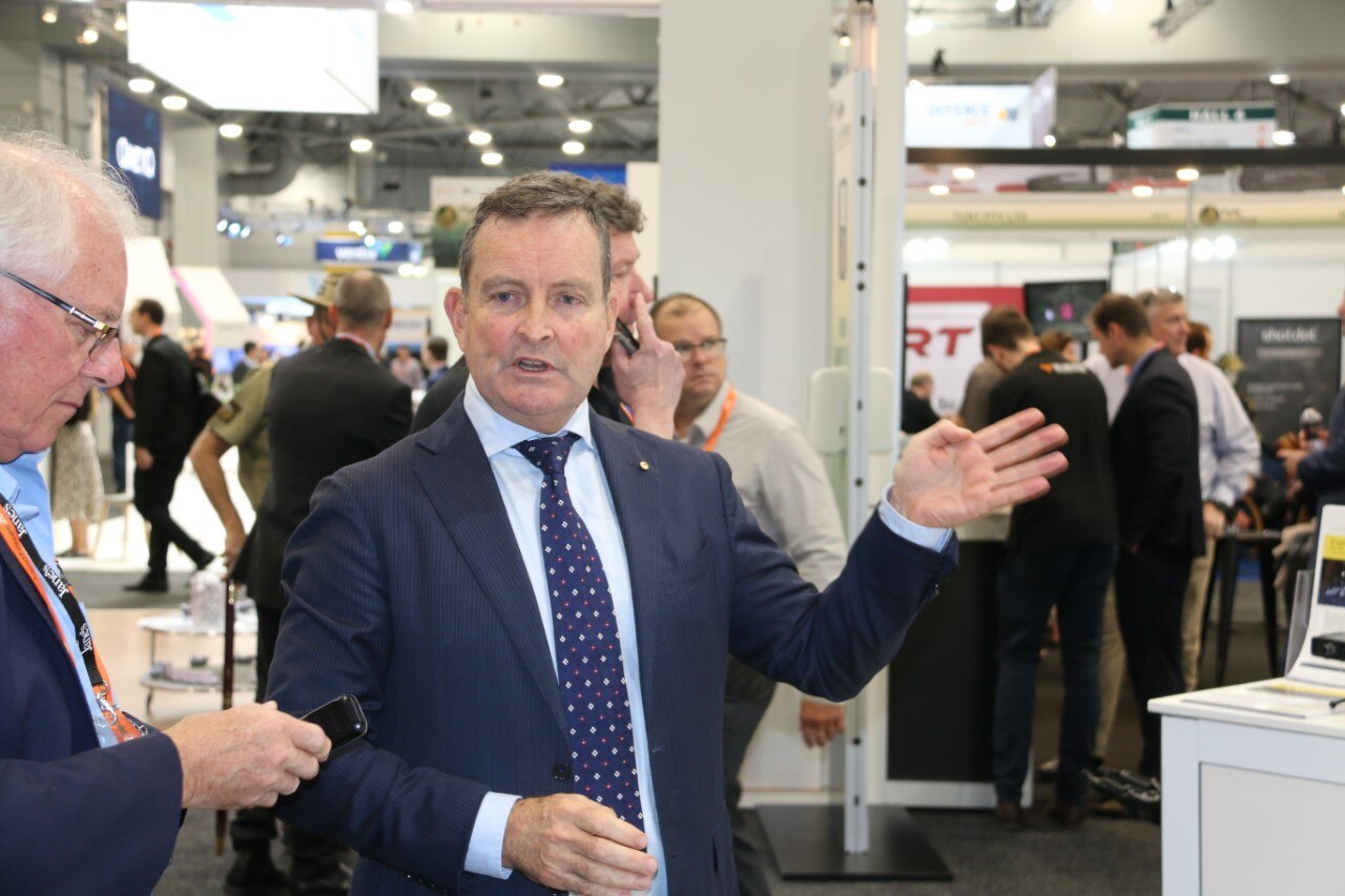 A man in a suit at a conference gestures with his hand.