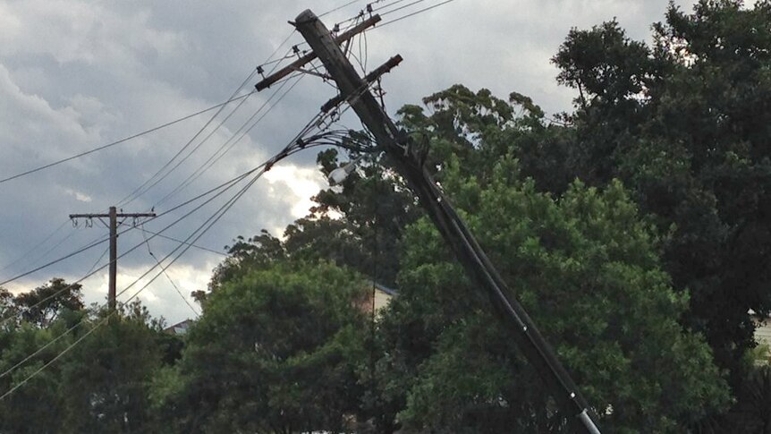 A damaged power pole leans over a car at Berkeley Vale