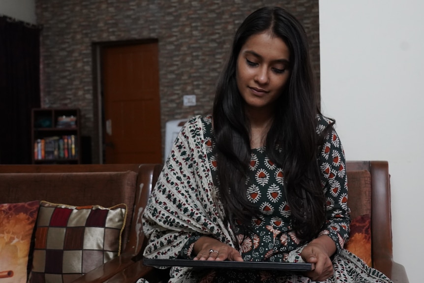 A young Indian woman looking down at a photo in a frame. 