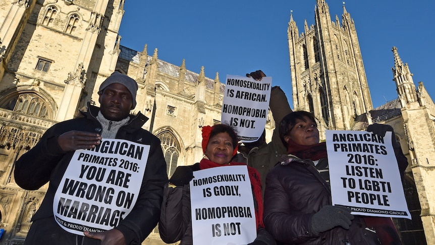 Four protesters hold signs outside the Canterbury Cathedral, saying things like 'Homosexuality is godly, homophobia is not'