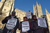 Four protesters hold signs outside the Canterbury Cathedral, saying things like 'Homosexuality is godly, homophobia is not'