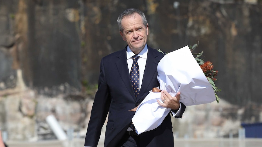 Bill Shorten walks towards the Opera House carrying a bouquet of flowers in his left arm