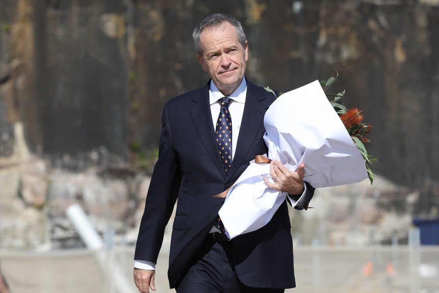 Bill Shorten walks towards the Opera House carrying a bouquet of flowers in his left arm