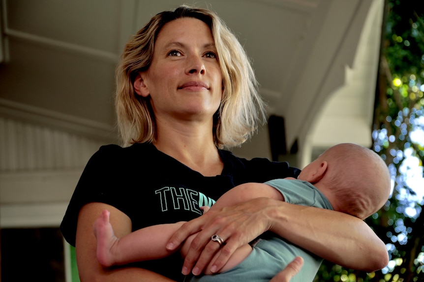 a woman holding her 2 month old baby smiling 