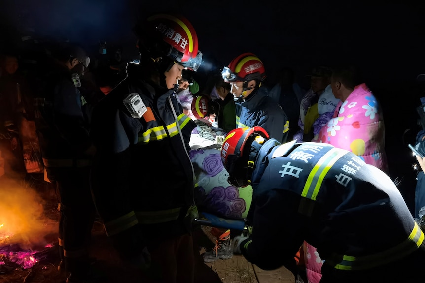 A team of rescuers at night carry a stretcher with the a rescued runner in Baiyin, Gansu province, China