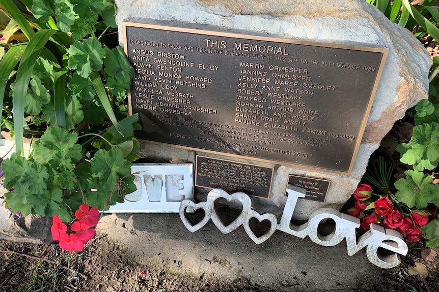 Flowers and signs spelling out LOVE surround the memorial for victims of the 1989 Cowper  bus crash.