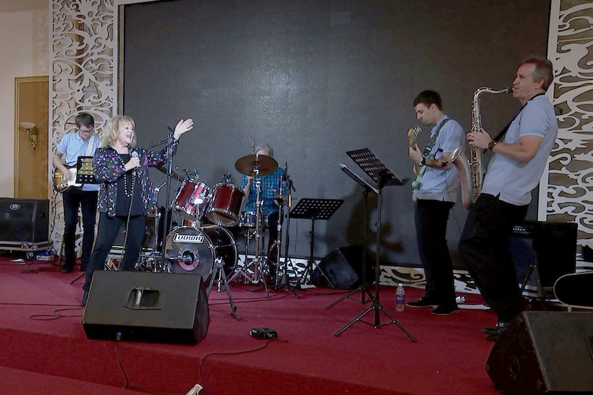 Little Pattie sings into a microphone while her band plays during a sound check in Vietnam.