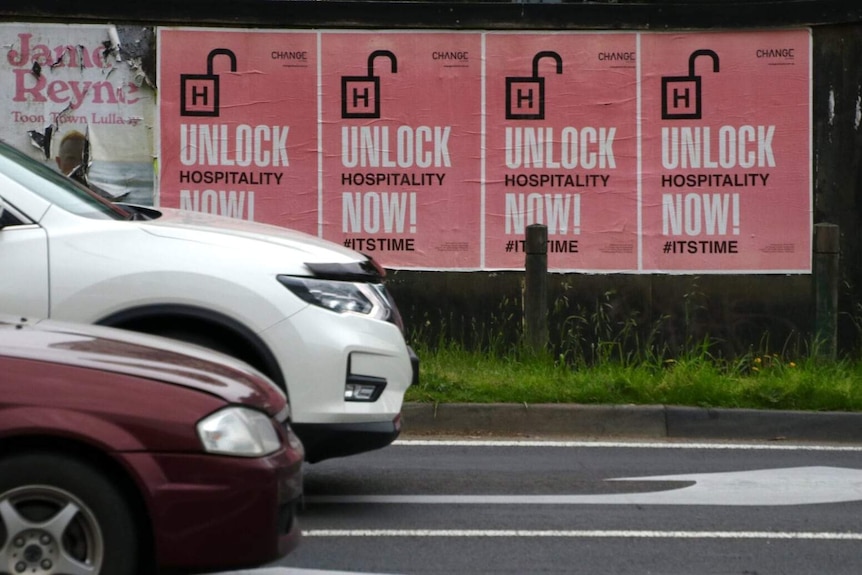 A poster by the side of a road says 'Unlock hospitality now.'